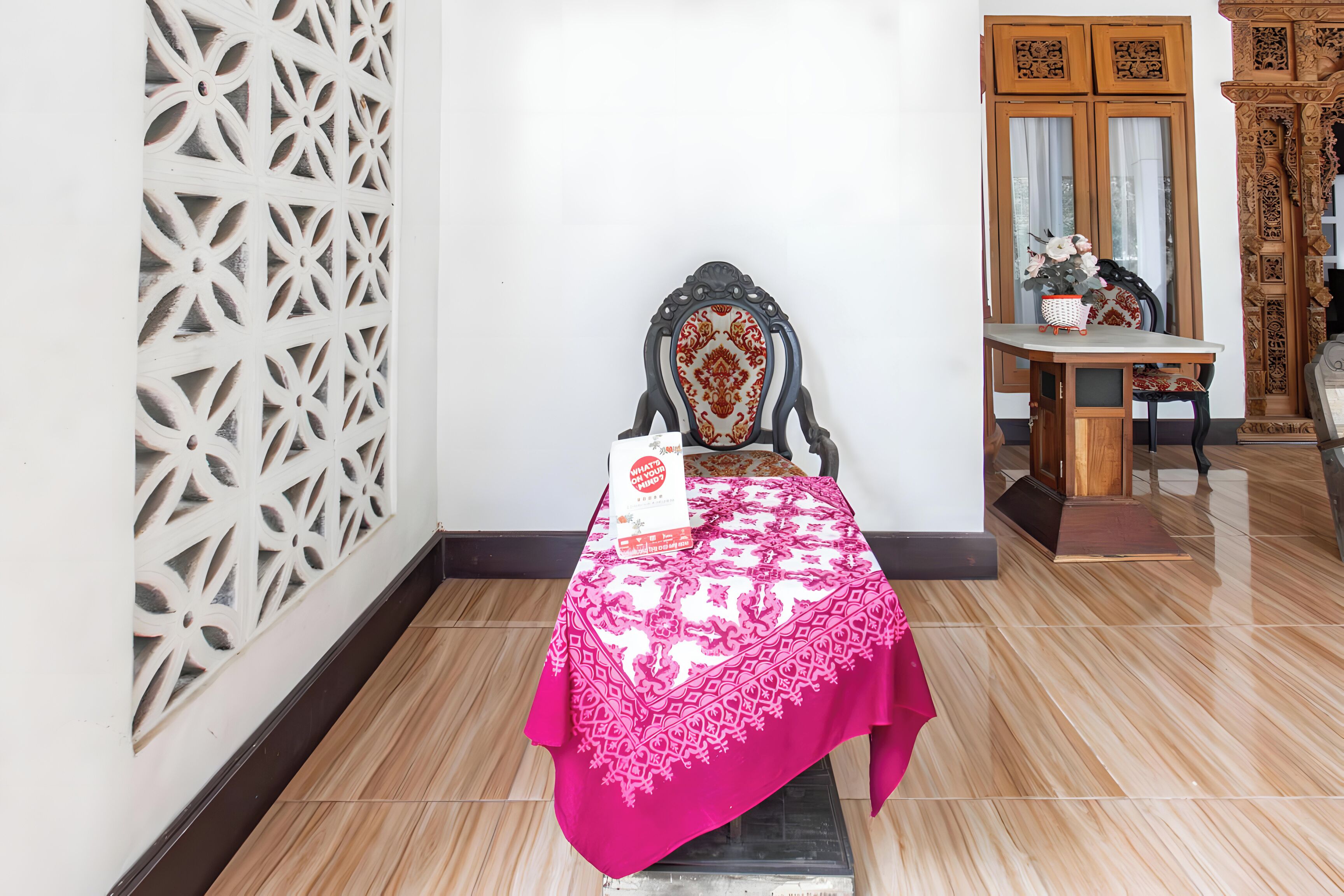 A room with a bed, a table with a book, and a decorative wall panel.