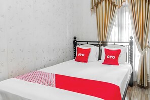 A bed with a white and red bedspread, two red pillows with the word 'OYO' on them, and a patterned wall. - Hotel O Homestay Bonjeruk Near Restoran Pawon 21 Bonjeruk (Jonggat)