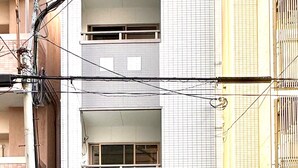 A multi-story building with a ground-level entrance, a visible balcony on the second floor, and a garage door on the right side. - 5-minute walk from Dotonbori and Kuromon Market, a famous sightseeing spot!  (大阪市)