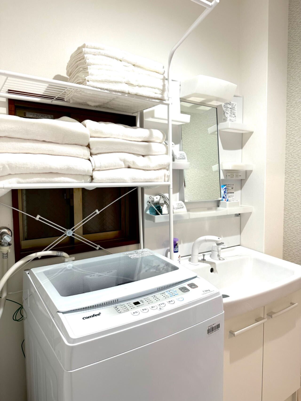 A hotel bathroom with a white sink, a mirror, and a stacked towel rack.
