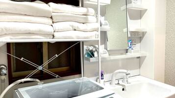 A hotel bathroom with a white sink, a mirror, and a stacked towel rack.