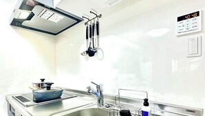 A modern kitchen with a stainless steel sink, a built-in stove, and overhead cabinets. - 5-minute walk from Dotonbori and Kuromon Market, a famous sightseeing spot!  (大阪市)