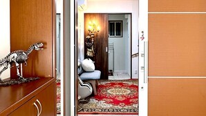 A hallway with a wooden wardrobe, a red patterned carpet, and a small dinosaur figurine on the floor. - 5-minute walk from Dotonbori and Kuromon Market, a famous sightseeing spot!  (大阪市)