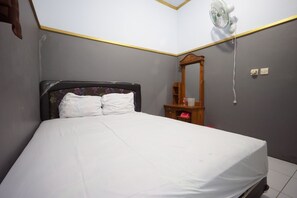 A bedroom with a bed, a bedside table, a mirror, and a wall-mounted fan.