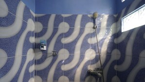 A bathroom with blue and white patterned tiles, a showerhead, and a handheld shower attachment. - SPOT ON 93620 Anisa Homestay Syariah Near Pantai Gemah Tulungaggung (Tulungagung)