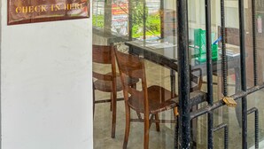 A glass partition with a metal grid, a wooden chair, and a sign on the wall. - ME Rooms Ubud (Ubud)