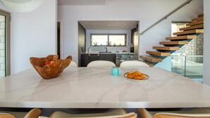 A modern kitchen with a marble countertop, a wooden bowl, and a plate of pastries. - Seawhisper Villa in Paxi (Paxos)