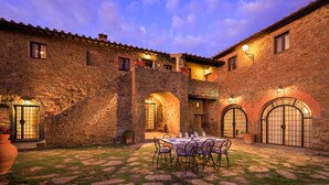 A courtyard with stone walls, arched doorways, and a table set for dining. - Villa Le Tornaie 14 Emma Villas (Monte San Savino)