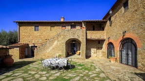 A stone building with a courtyard, outdoor seating, and a staircase leading to the entrance. - Villa Le Tornaie 14 Emma Villas (Monte San Savino)