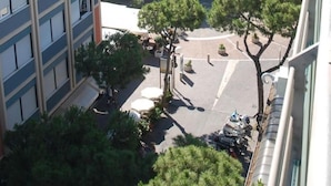 A high-rise building with a courtyard featuring a carousel, surrounded by trees and other buildings. - Bamb in Panoramica (Cattolica)