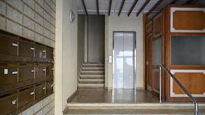 A staircase leading to a door, with a metal railing on the right and a wall of filing cabinets on the left. - Bamb in Panoramica (Cattolica)