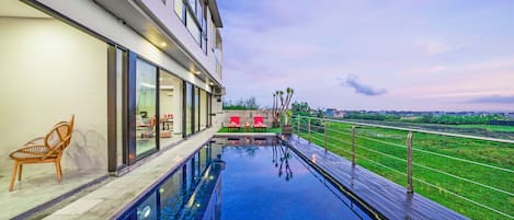 Un hotel moderno con piscina infinita en la azotea, asientos al aire libre y vistas del paisaje circundante.