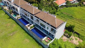 Ein modernes mehrgeschossiges Haus mit Pool, großen Fenstern und einem gepflegten Rasen.