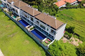 Une maison moderne à plusieurs étages, dotée d’une piscine, de grandes fenêtres et d’une pelouse bien entretenue.