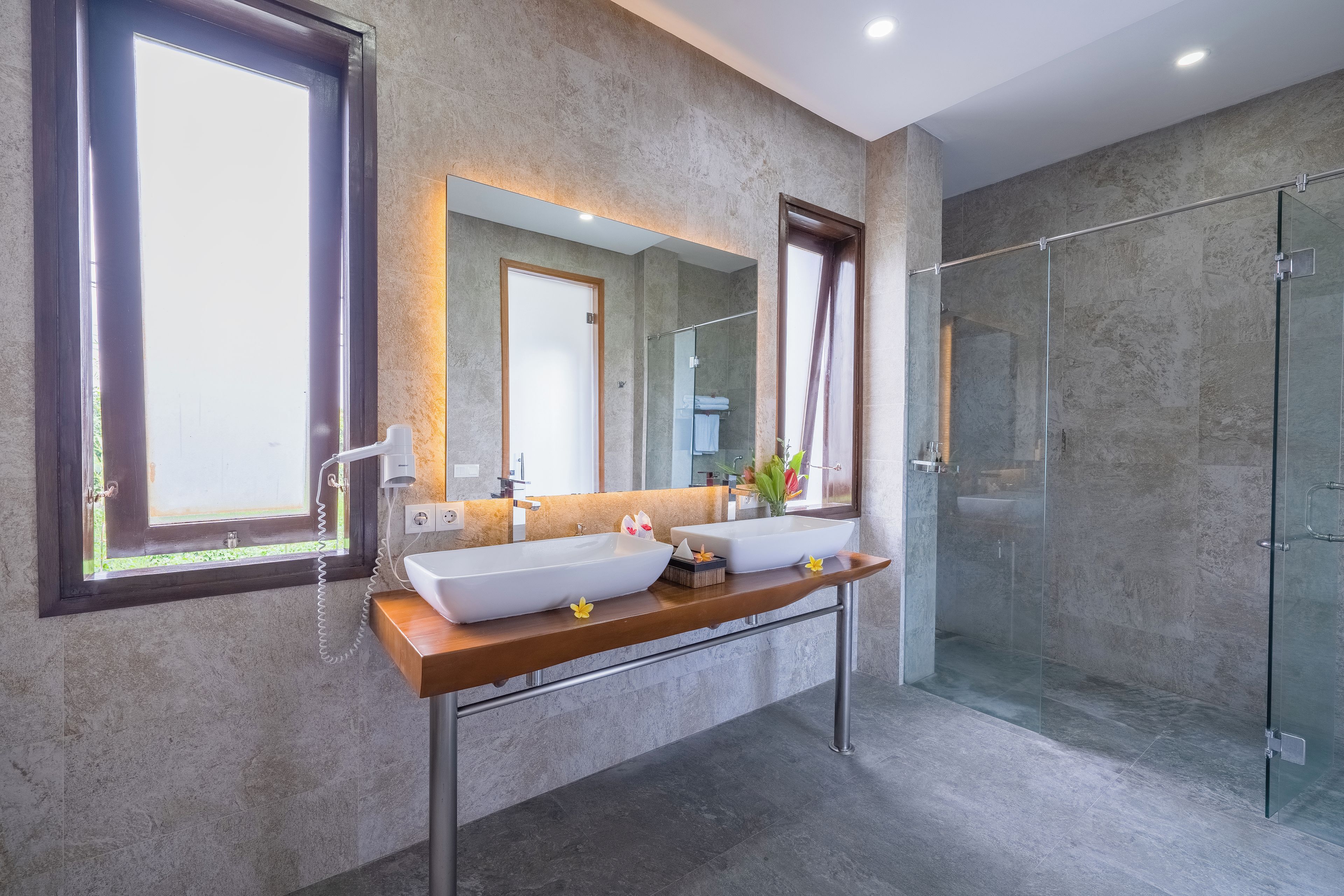 A modern bathroom with two large sinks, a glass shower enclosure, and a large mirror.