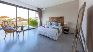 Ein modernes Hotelzimmer mit einem großen Bett, einem Balkon mit Blick und einem Holzsessel.