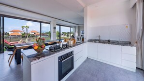 Eine moderne Küche mit einer großen Kochinsel, einem eingebauten Backofen und Blick ins Freie.