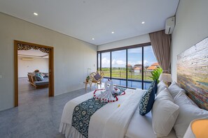A modern bedroom with a large bed, a view of the outdoors, and a balcony. - Villa Emilia Seminyak by Nagisa Bali (Kerobokan)