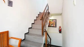 A staircase with a wooden handrail and a fire extinguisher mounted on the wall. - Hotel Djagalan Raya  (Surabaya)