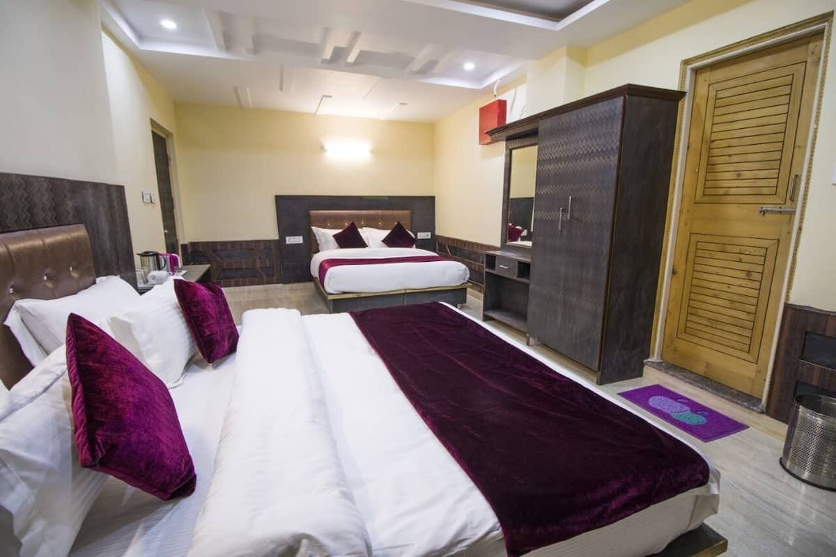 Habitación de hotel con dos camas, un armario, un espejo y una puerta.