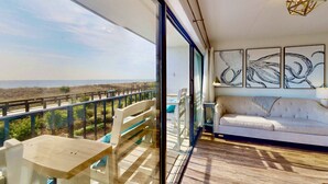 A balcony with a table and chairs, a sofa, and abstract wall art.