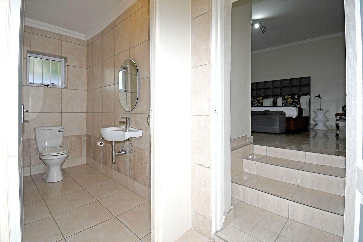 Un baño con inodoro, lavamanos y espejo.