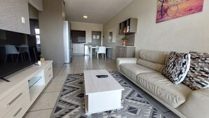 A modern living room with a flat-screen TV, a sofa, a coffee table, and a patterned rug. - Zwelakho Luxury  furnished apartments (Sandton)