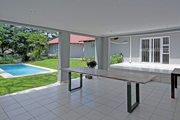 A spacious patio with a pool, a barbecue grill, and a dining table. - Zwelakho Luxury furnished apartments (Sandton)