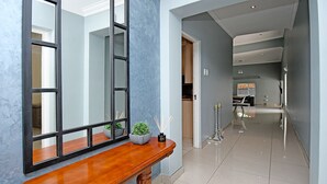 A hallway with a wooden console table, a mirror, and a potted plant. - Zwelakho Luxury  furnished apartments (Sandton)