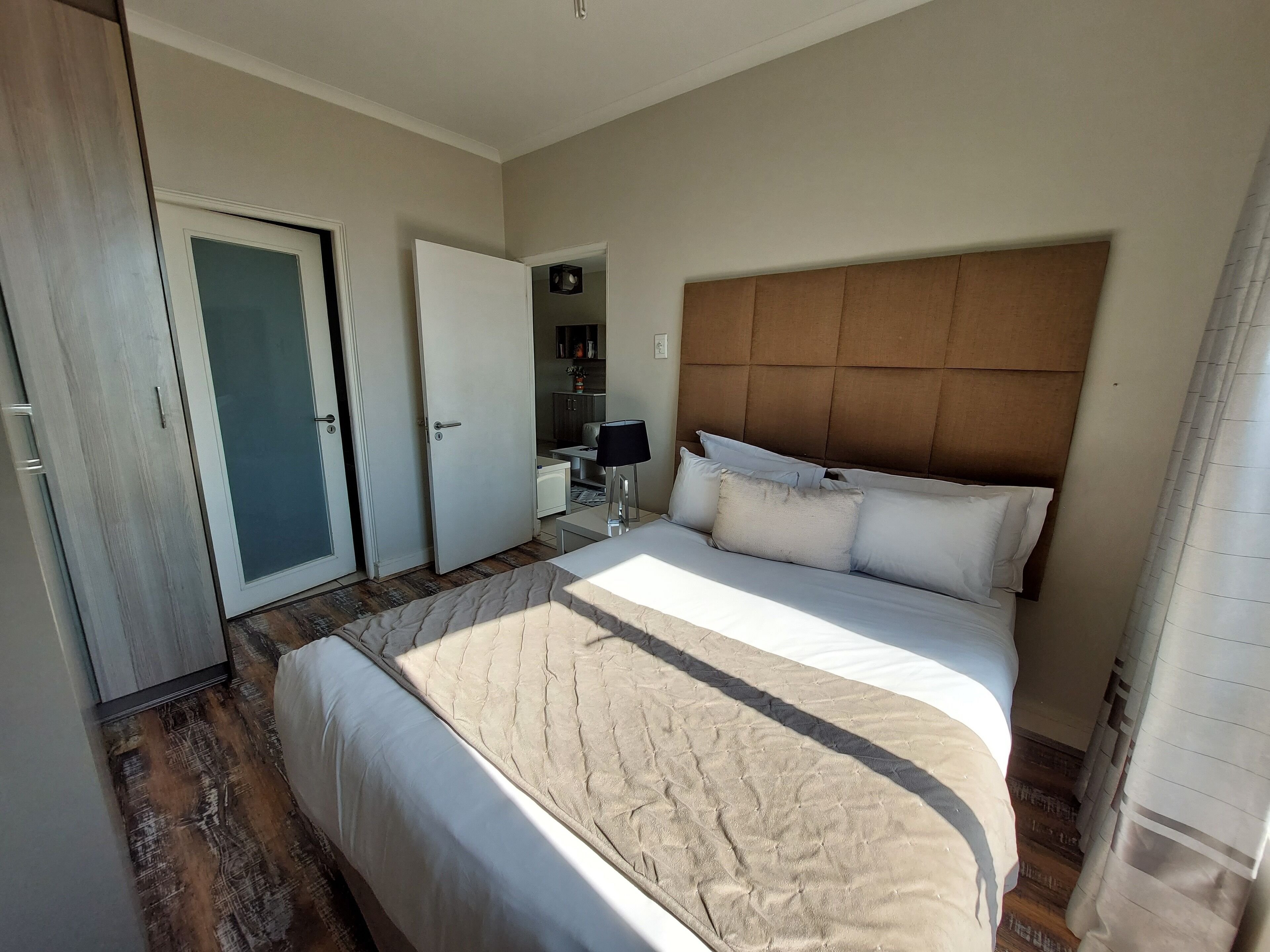 A bedroom with a large bed, a wardrobe, and a bathroom visible through an open door.