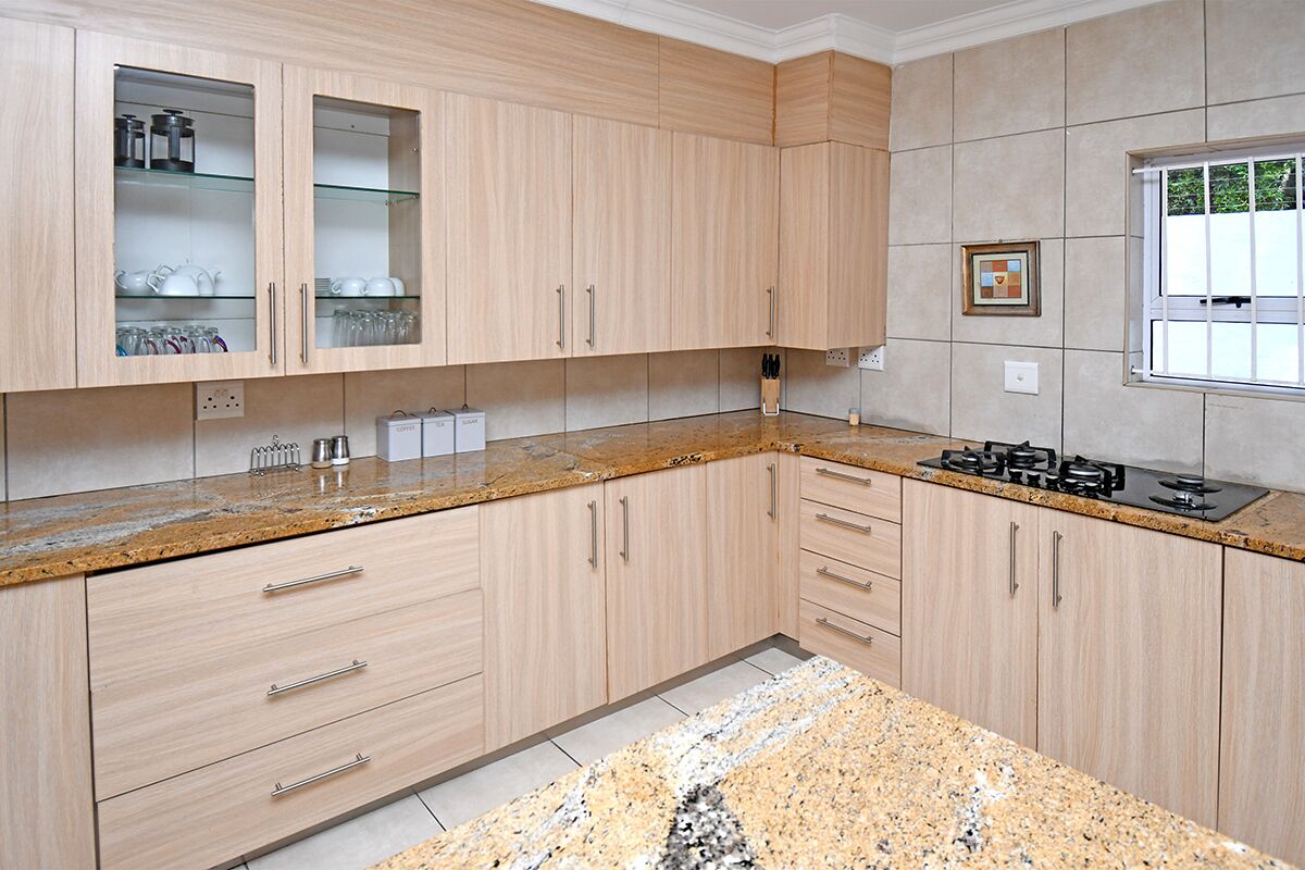 A kitchen with light wood cabinets, granite countertops, and a gas stove.