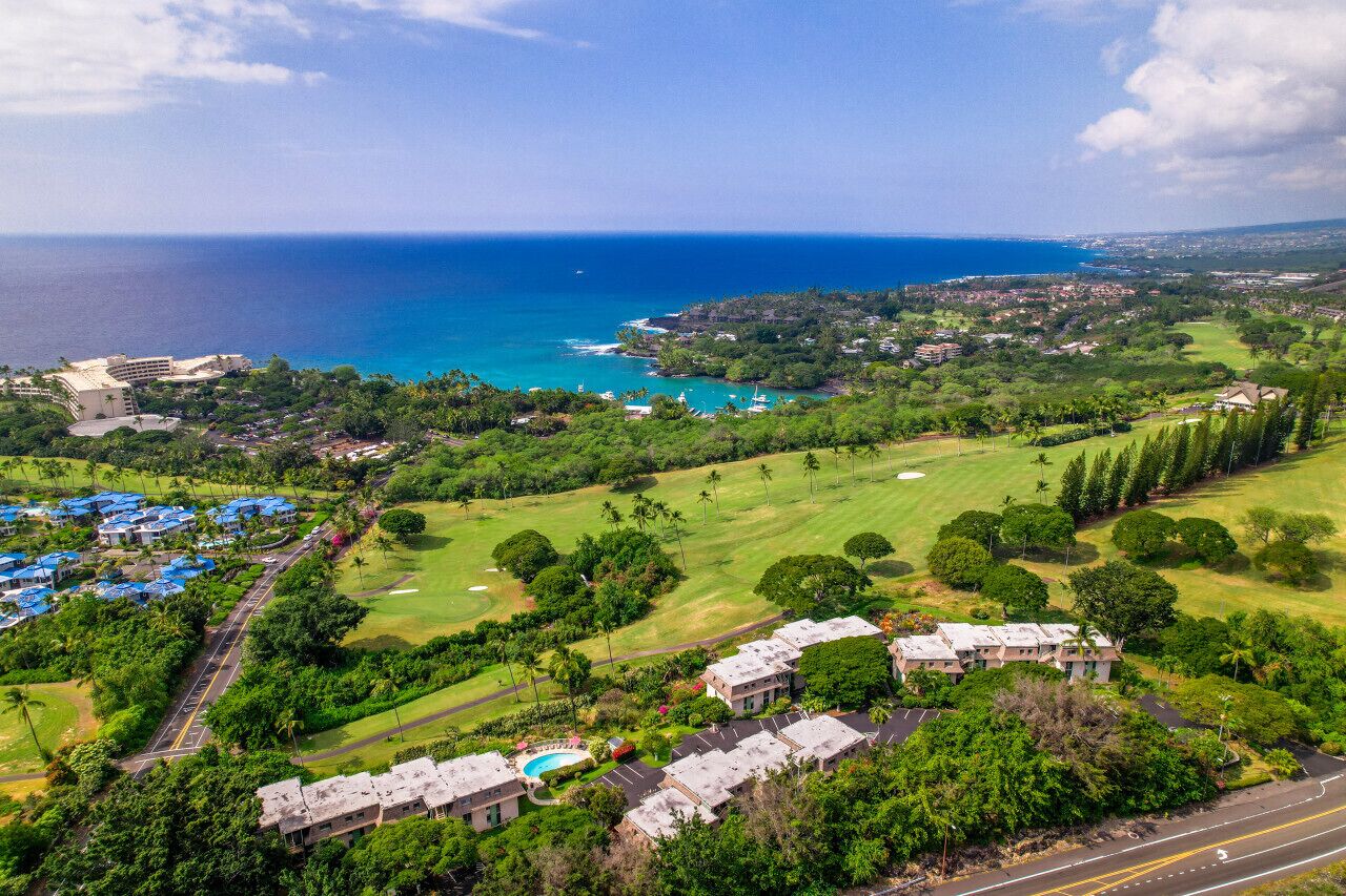 An aerial view of a coastal resort with a golf course, beachfront properties, and a clear view of the ocean.