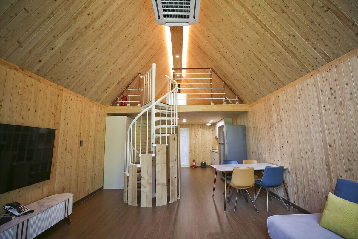Un interior de madera con una escalera de caracol, un comedor y una zona de estar.