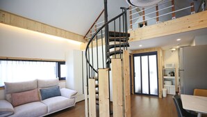 Un interior moderno con una escalera de madera, un sofá y una zona de comedor.