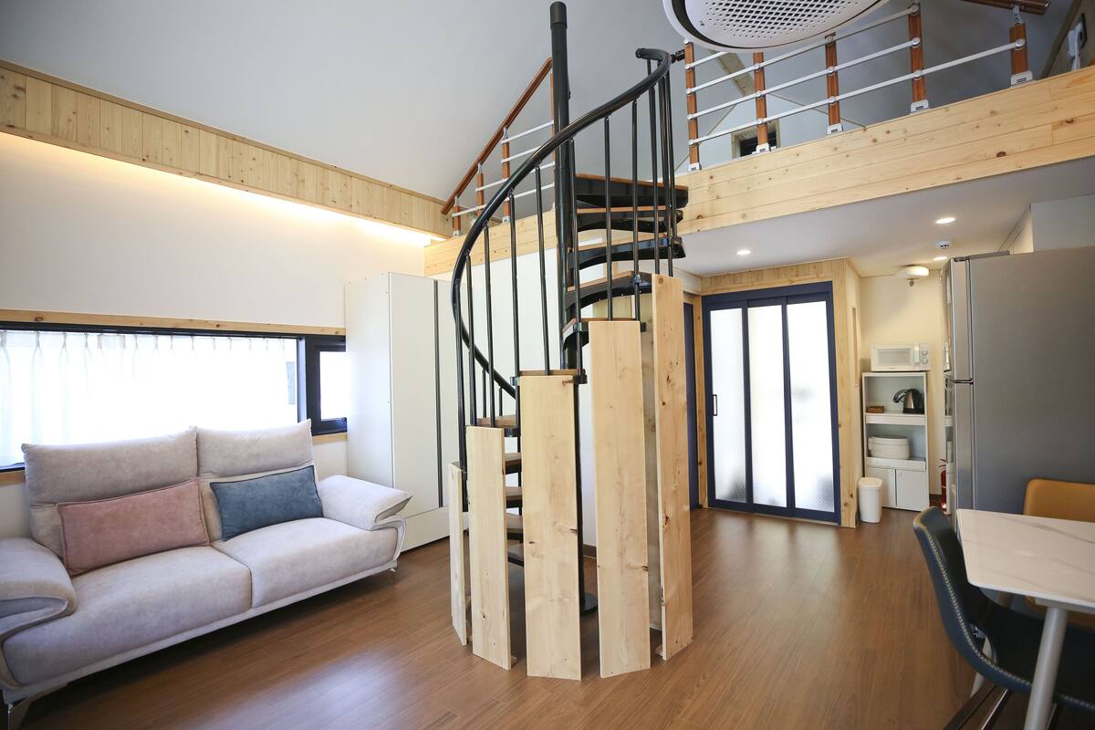 Un interior moderno con una escalera de madera, un sofá y una zona de comedor.