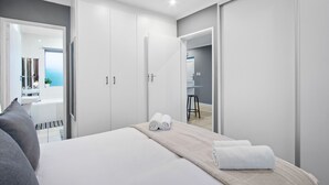 Et moderne hotelværelse med en seng, et siddeområde og et badeværelse, der kan ses gennem en åben dør.