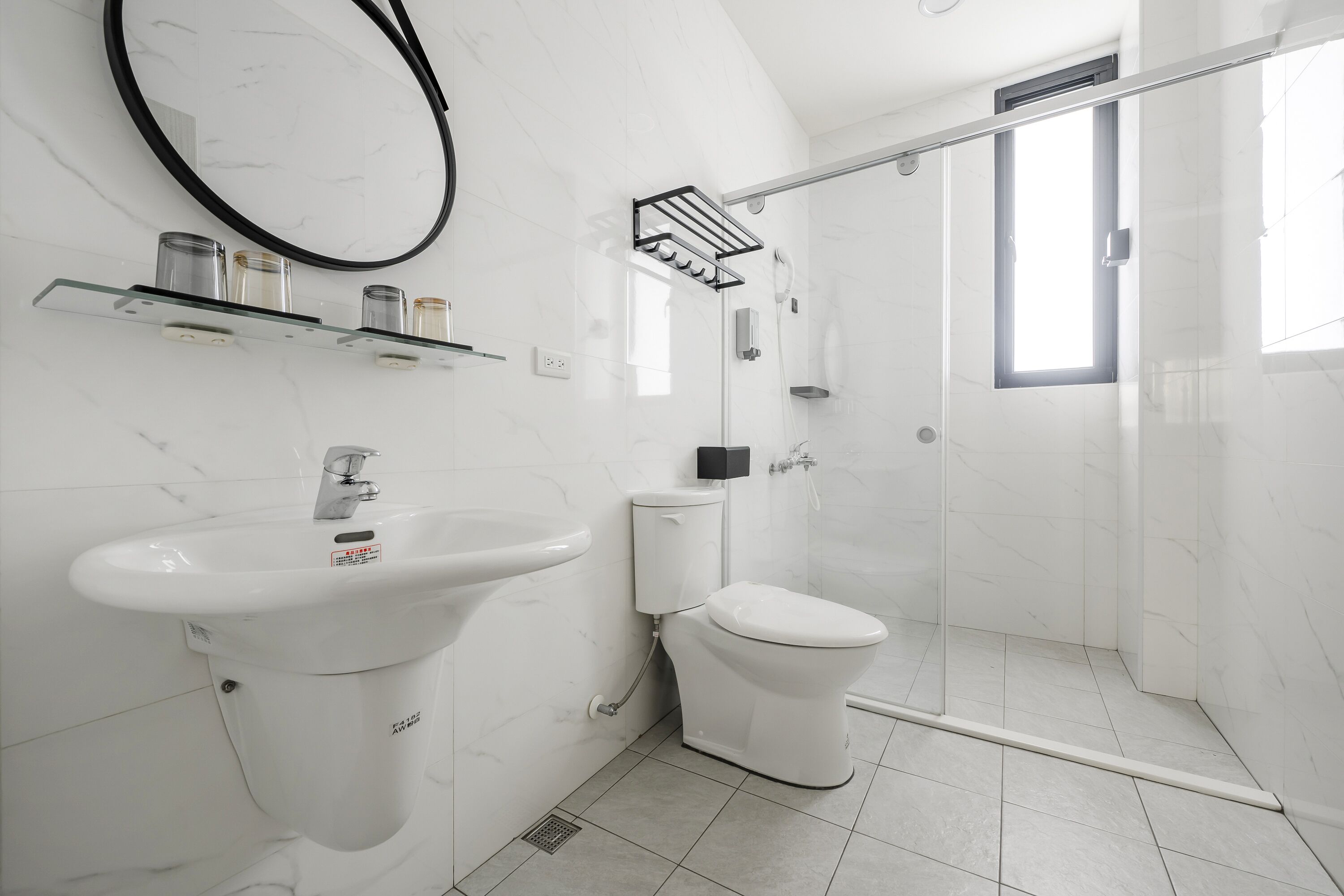 Un baño moderno con lavamanos, inodoro y ducha de mármol blanco.