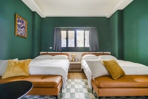 A hotel room with two beds, a small table, and a window with curtains.