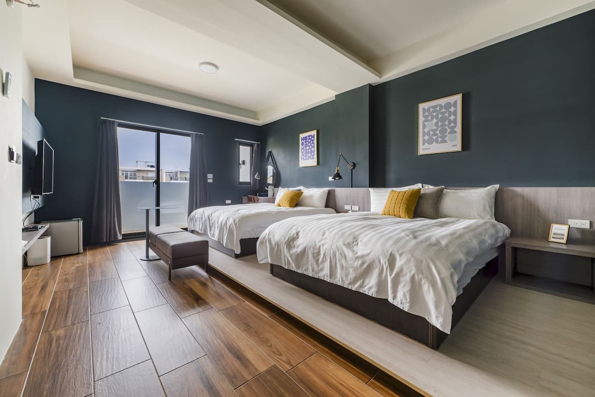 Ein modernes Hotelzimmer mit zwei Betten, einem Balkon und einem großen Fenster.
