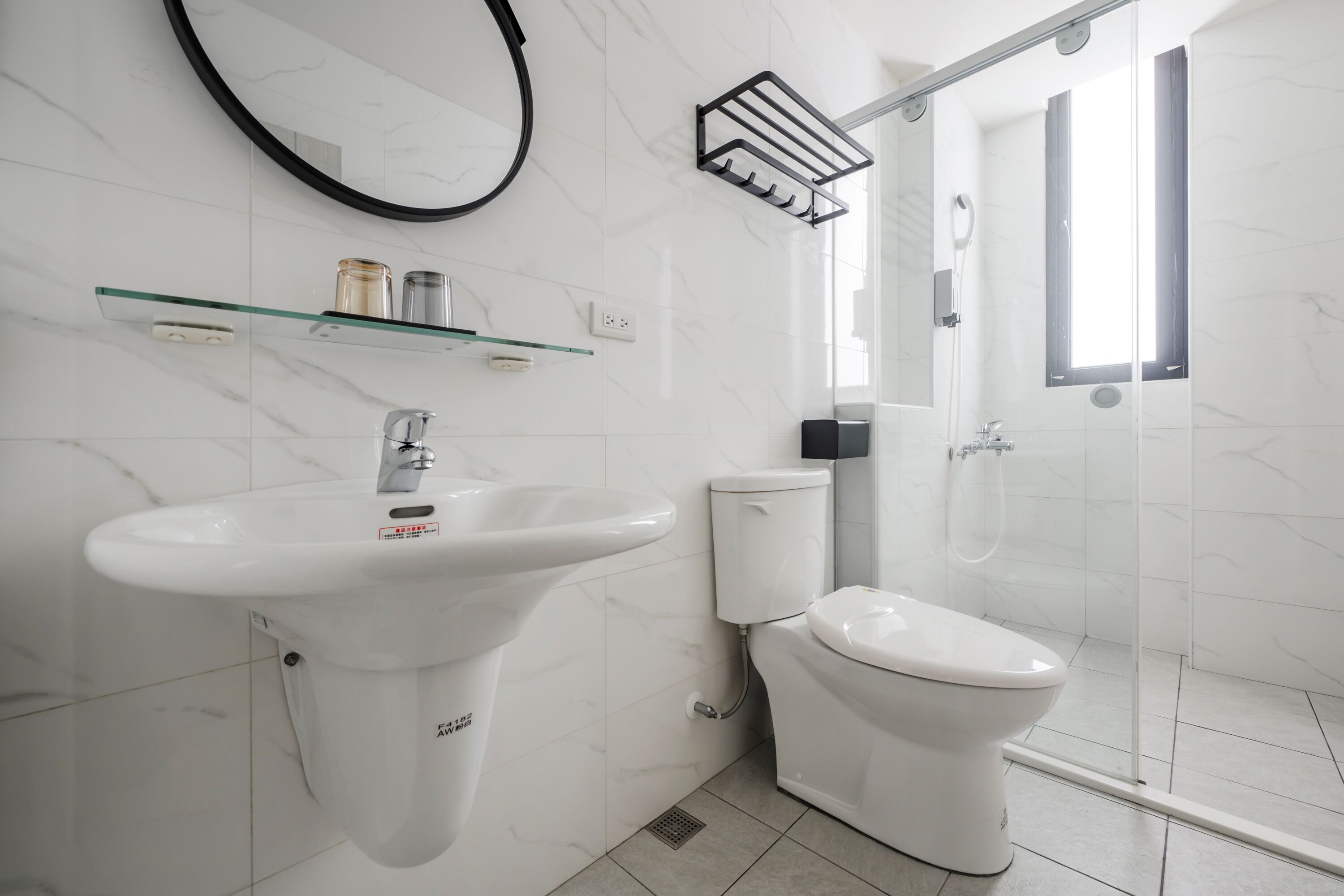 A modern bathroom with a white sink, toilet, and glass shower enclosure.