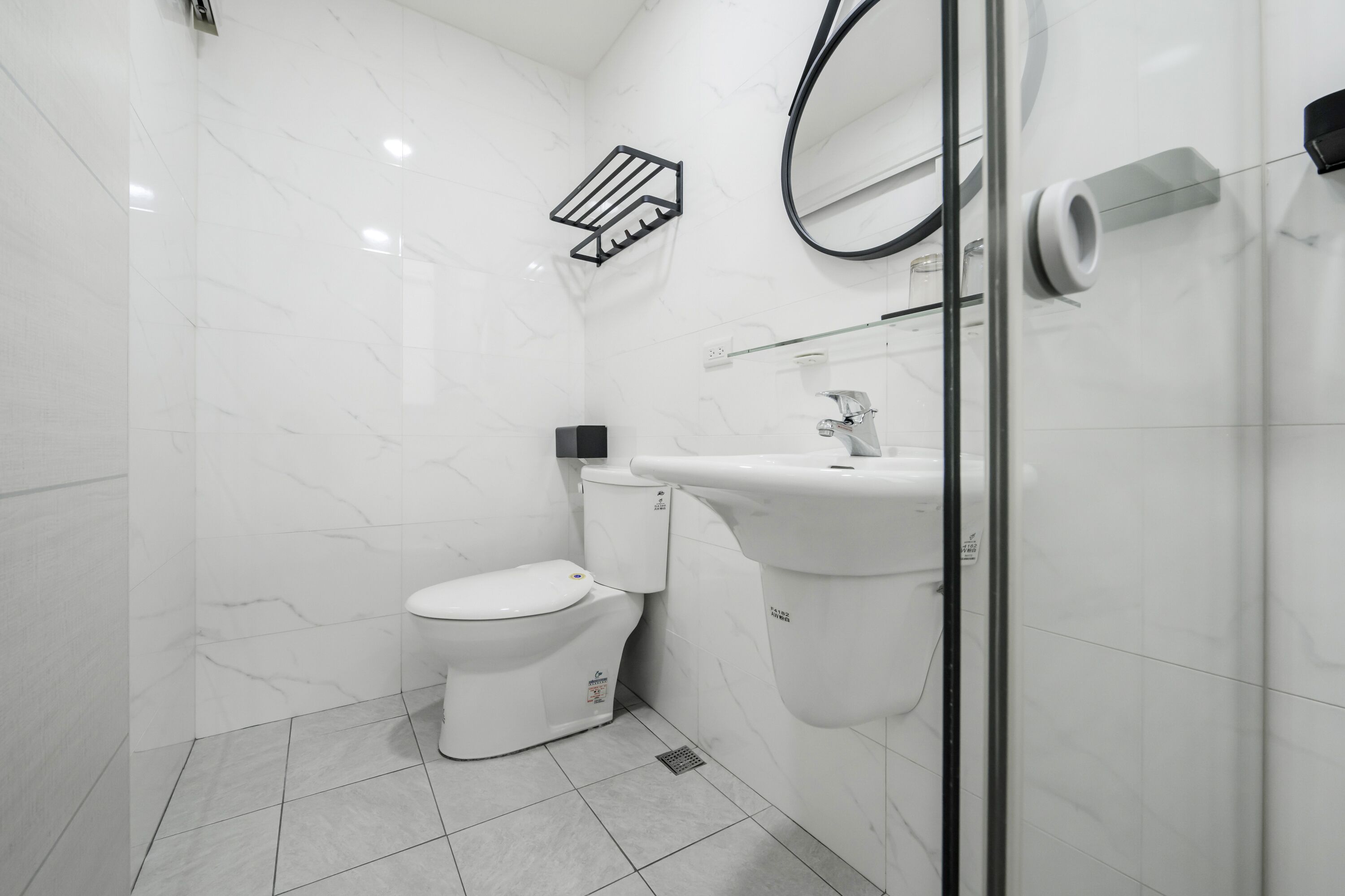 A modern bathroom with a toilet, sink, and glass shower enclosure.