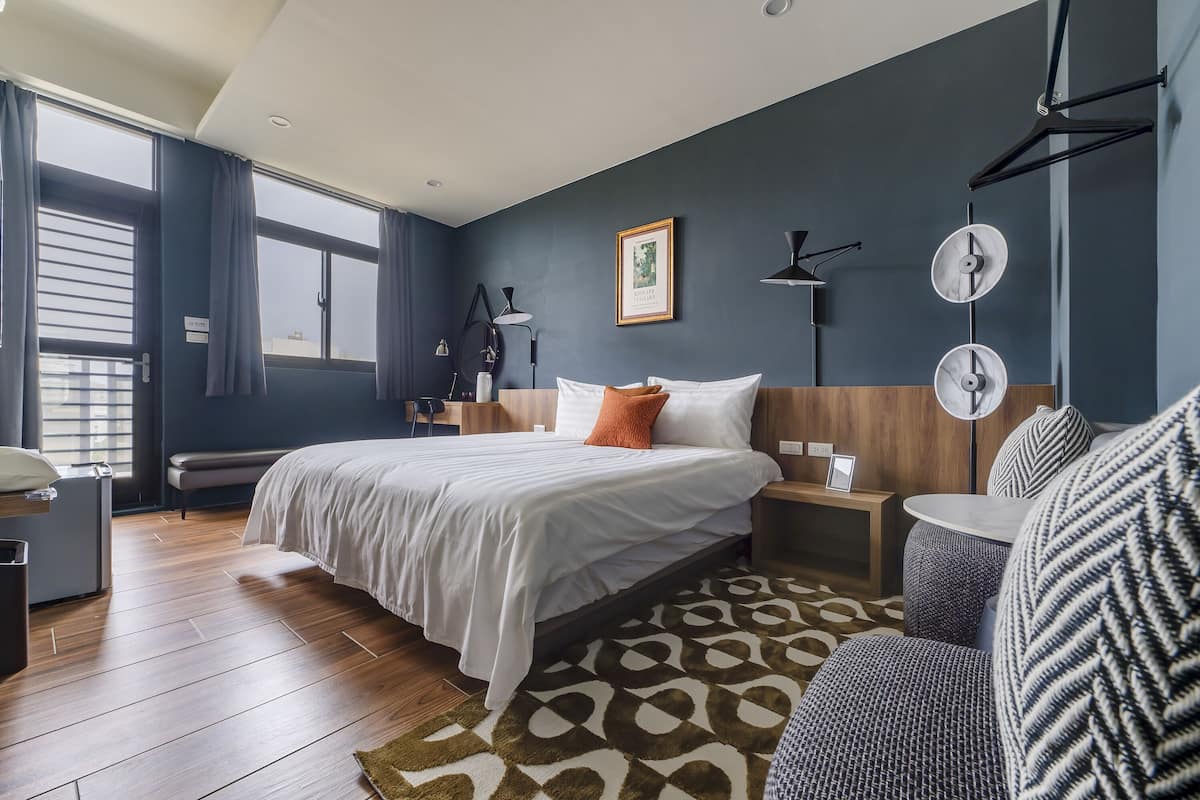 Ein modernes Hotelzimmer mit einem großen Bett, Nachttischen, einem Schreibtisch und einem Sofa.