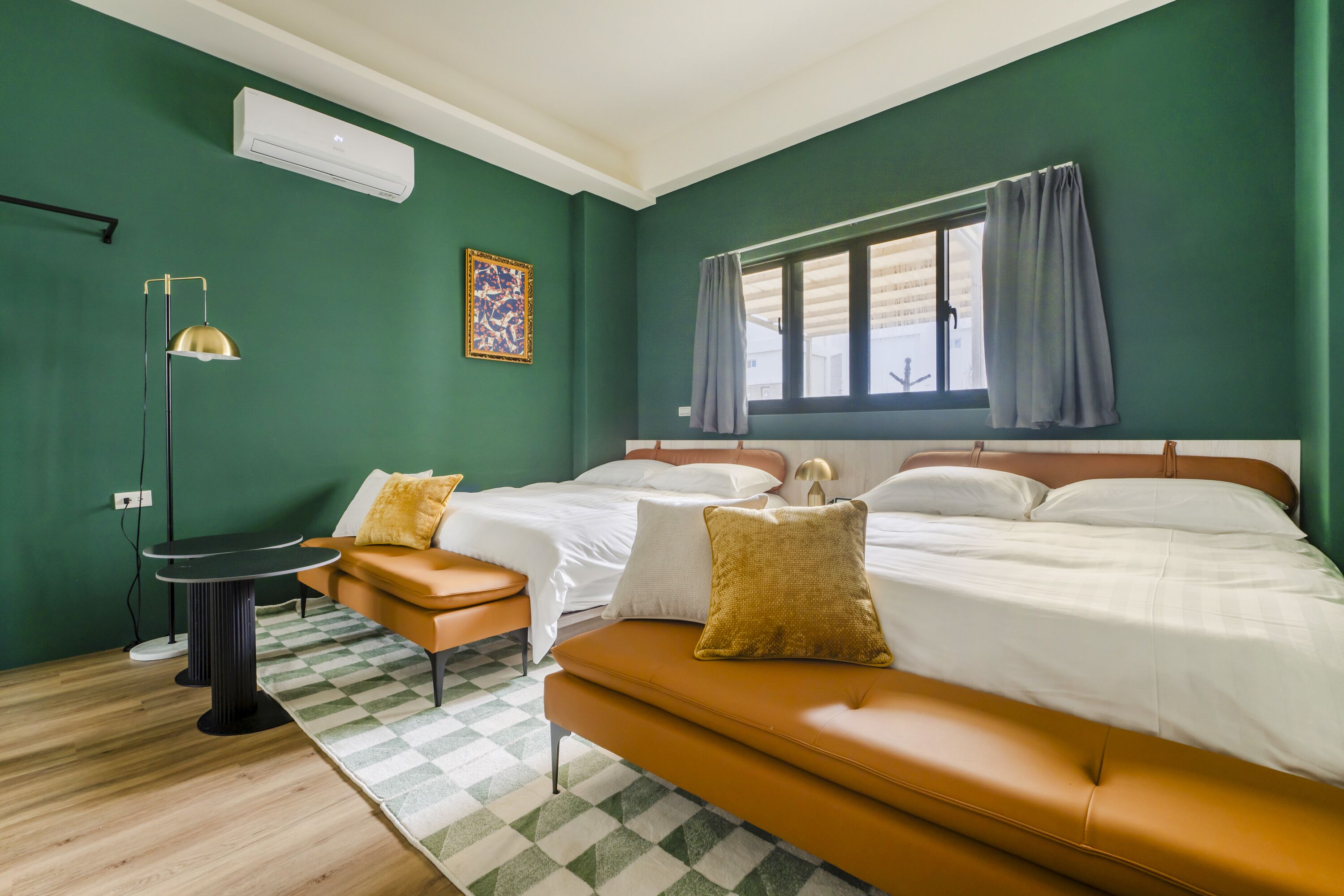 A room with two beds, a sofa, a small table, and a floor lamp.