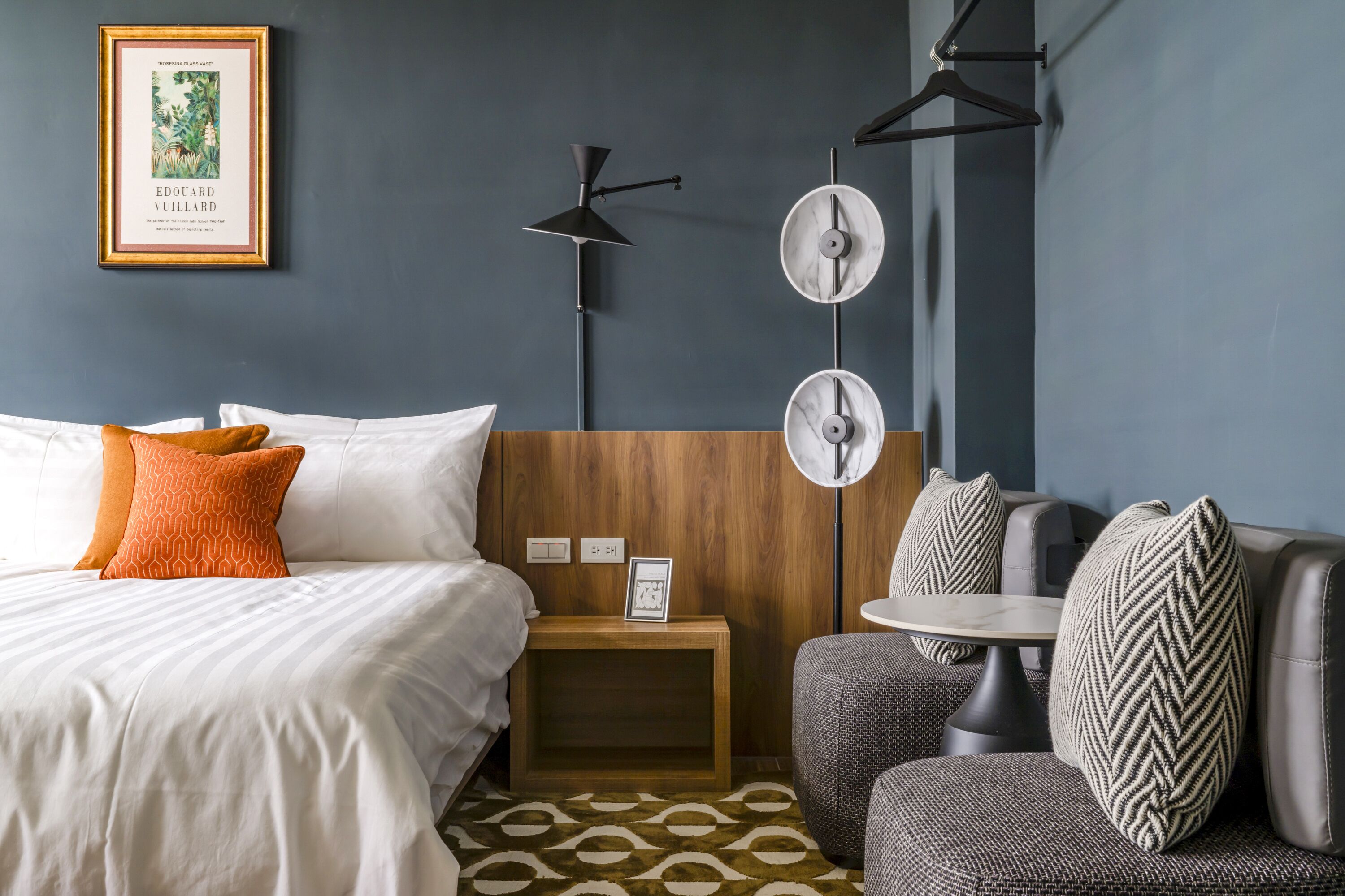 A hotel room with a bed, a nightstand, a table, and a sofa.