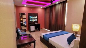 Habitación de hotel con cama, escritorio, televisión y una pequeña zona de estar.