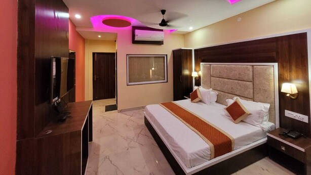 Una habitación de hotel moderna con una cama grande, un televisor e iluminación circular en el techo.
