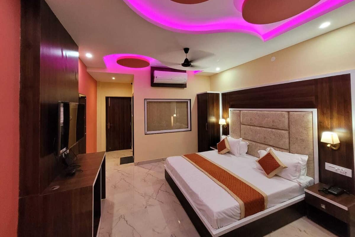 Una habitación de hotel moderna con una cama grande, un televisor e iluminación circular en el techo.