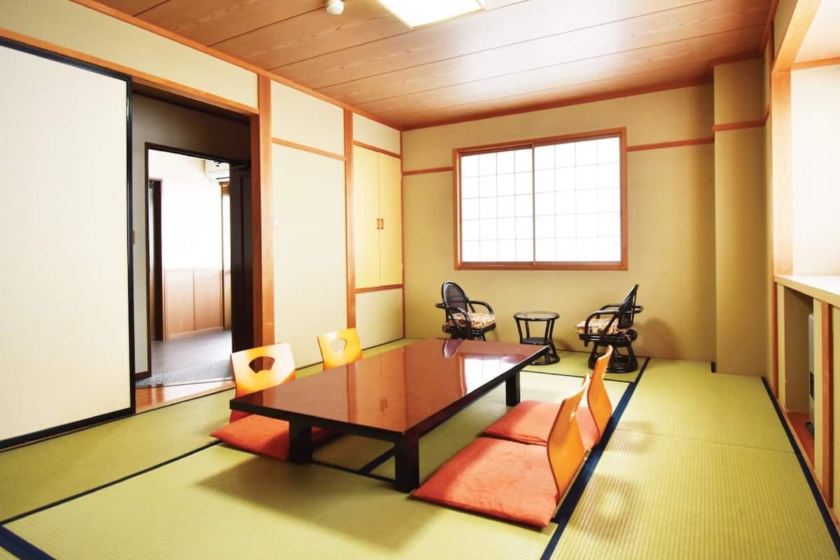 A tatami mat room with a low table, chairs, and a window.