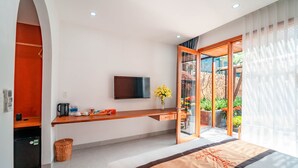 A modern hotel room with a bed, a TV, a small desk with a kettle, and a view of the outdoors. - TRUONG PHU HOUSE (Hue)