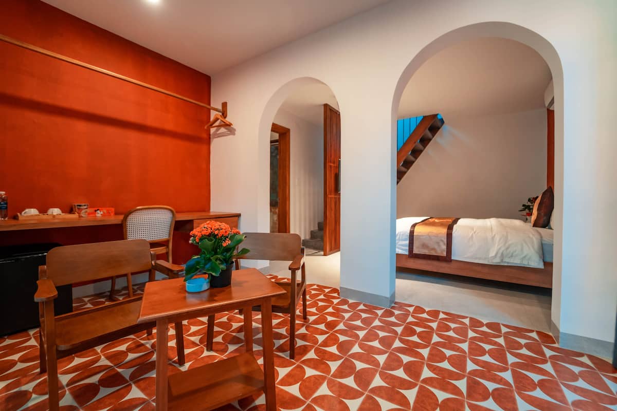A compact room with a dining area, a bed, and a staircase.